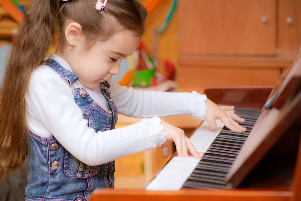 Liten flicka spelar piano — Stockfoto