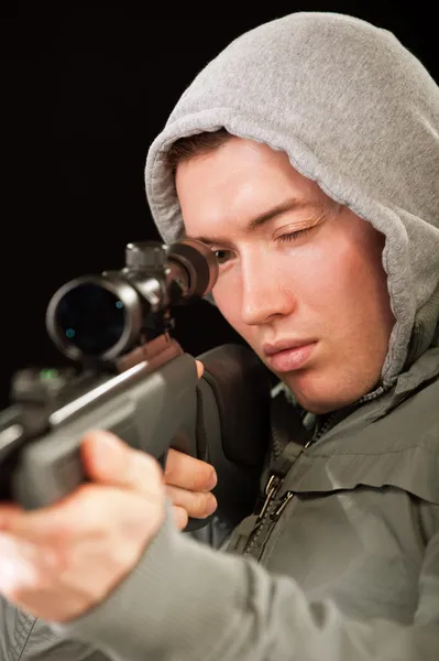 Sniper in hood aims at rifle — Stock Photo, Image