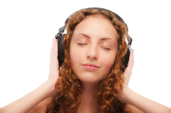 Menina encaracolado bonita ouve música através de fones de ouvido — Fotografia de Stock