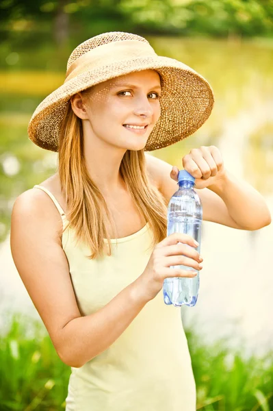 Girl in straw hat drinks water — Stock Photo, Image