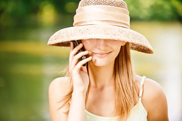 Flicka i stråhatt med telefon — Stockfoto