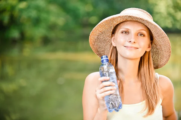 Chica en sombrero de paja bebe agua — Foto de Stock