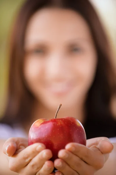 Jovem mulher estica maçã — Fotografia de Stock
