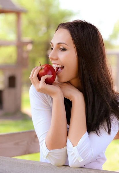 Junge Frau beißt in Apfel — Stockfoto
