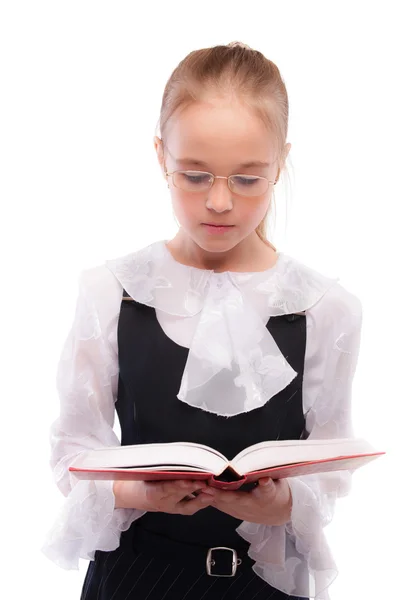 Молода усміхнена школярка читає підручник — стокове фото