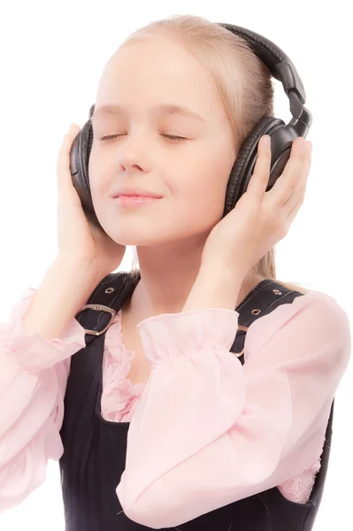 Ung vacker skolflicka lyssnar på musik i örat-telefoner — Stockfoto