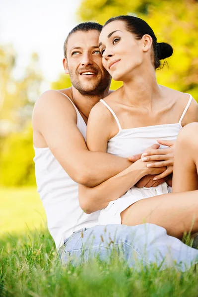 草の上に座っている若い美しいカップル — ストック写真