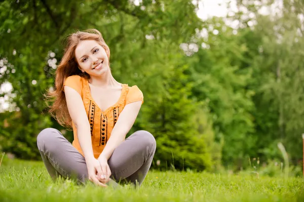 Vacker flicka sitter på gräsmattan — Stockfoto
