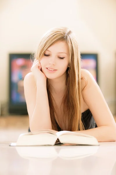 Улыбающаяся девушка читает толстую книгу — стоковое фото