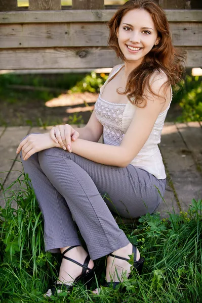Schönes Mädchen sitzt auf Holzboden — Stockfoto