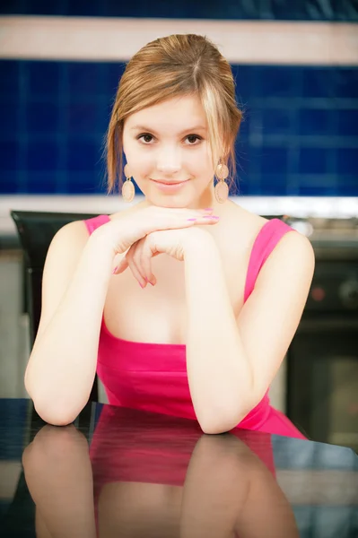 Meisje in een rode jurk zit aan tafel — Stockfoto