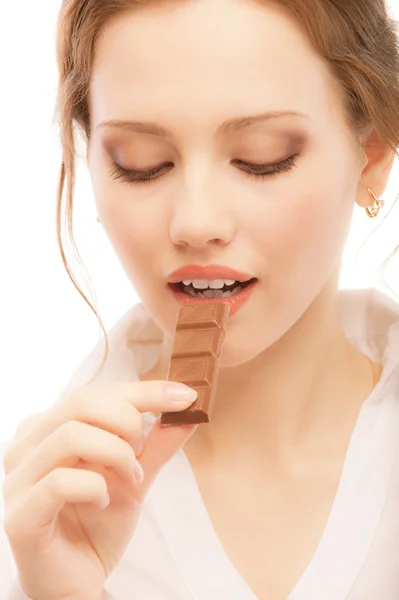 Schöne junge Frau beißt Schokolade ab — Stockfoto
