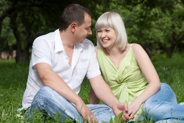 幸福的情侣坐在草地上 — 图库照片