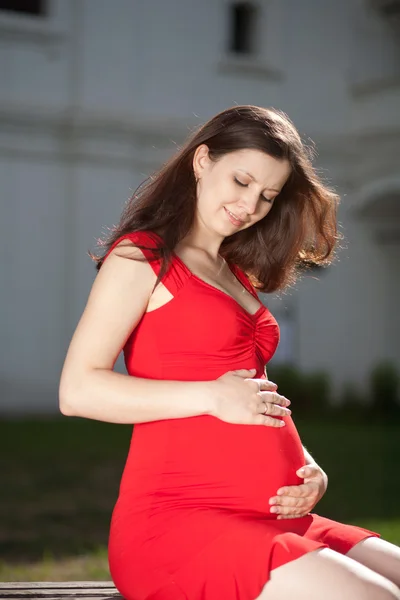 Bella donna incinta in abito rosso — Foto Stock