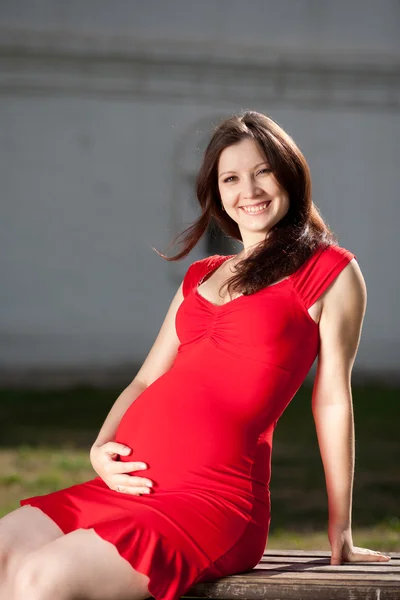 Беременная женщина сидит на открытом воздухе — стоковое фото