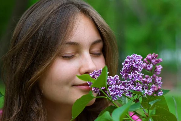 Adolescente chica oliendo lilas — Foto de Stock