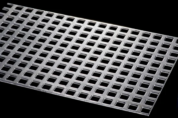 Punched metal isolated on black — Stock Photo, Image