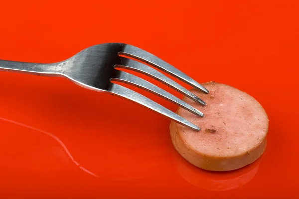 Cutting frankfurter on red background — Stock Photo, Image