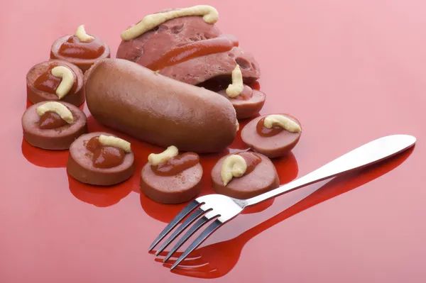 Cutting sausage on red — Stock Photo, Image