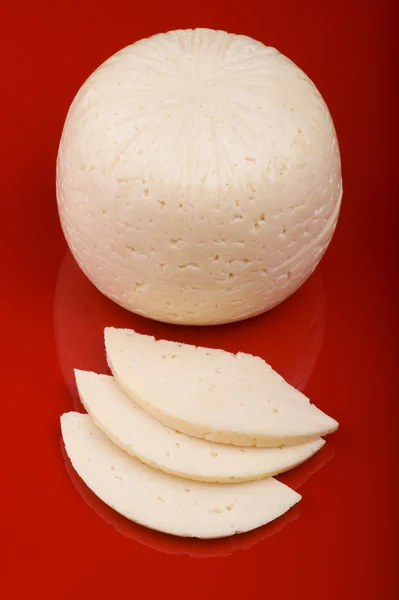 Corte de queijo no fundo vermelho — Fotografia de Stock