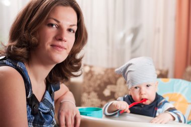 Portrait of young woman feeding her baby clipart