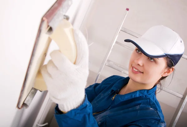 Молода жінка будівельник полірує стіну — стокове фото