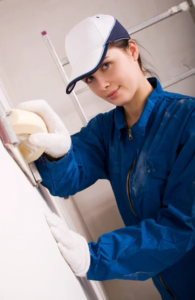 Молода жінка будівельник полірує стіну — стокове фото