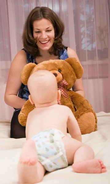 ベッドで男の赤ちゃんと遊ぶ若い母 — ストック写真