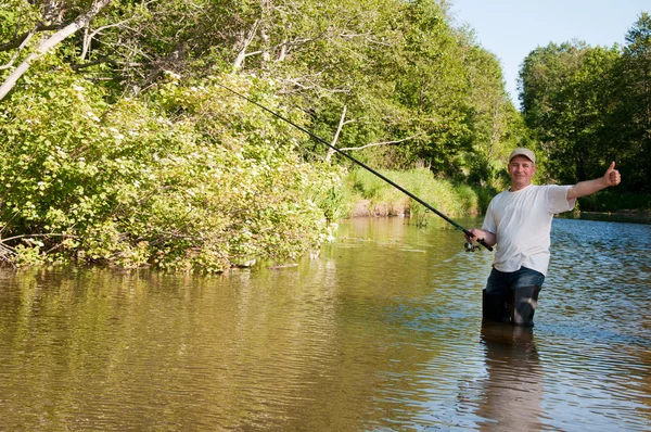 Un pescador pescando en un río — Foto de Stock
