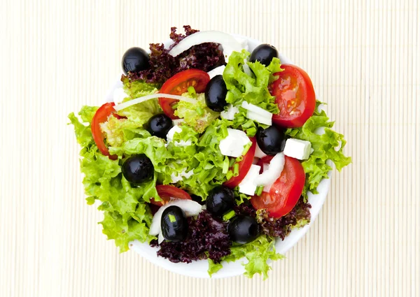 Salad in plate on bamboo mat — Stock Photo, Image