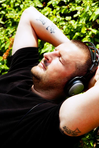 Człowiek z słuchawki słuchać muzyki w parku — Zdjęcie stockowe