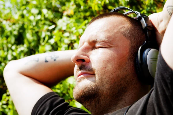 Muž se sluchátky, poslech hudby v parku — Stock fotografie