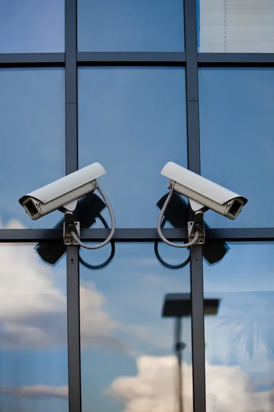 Две камеры видеонаблюдения на бизнес-здании с отражением — стоковое фото