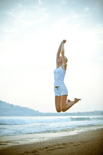 Happy young woman is jumping on the beach — Stock Photo, Image
