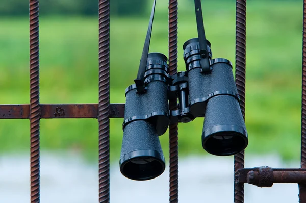 Binoculars hanging on metal grating — Stock Photo, Image