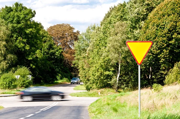 Výnos znamení nedaleko rozcestí a řítí auto — Stock fotografie