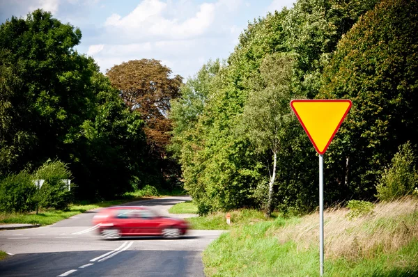 Знак врожаю біля перехрестя і поспішаючого автомобіля — стокове фото
