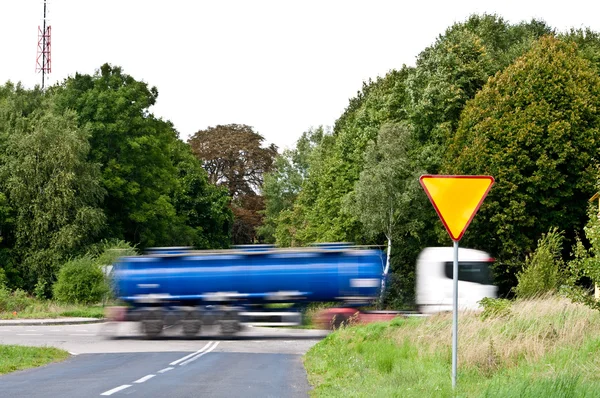 Доходность знак рядом с перекрестком и спешащий грузовик — стоковое фото