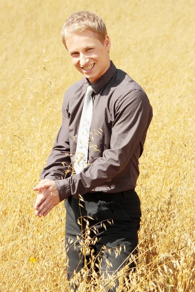 Farmer in suit standing in field of oats — Stock Photo, Image
