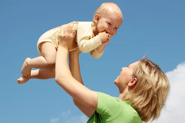 Moeder met baby onder de blauwe hemel — Stockfoto