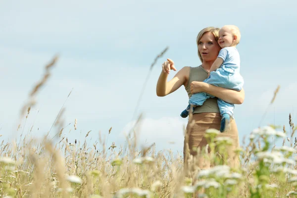 Vrouw met baby op haar schouders in een land — Stockfoto