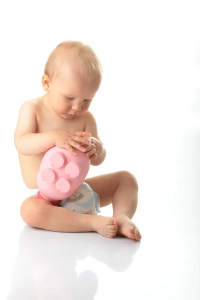 Jonge babyjongen spelen met roze piggy bank — Stockfoto
