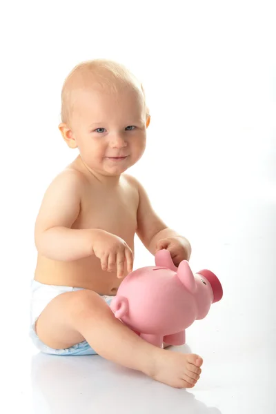 Jonge babyjongen spelen met roze piggy bank — Stockfoto