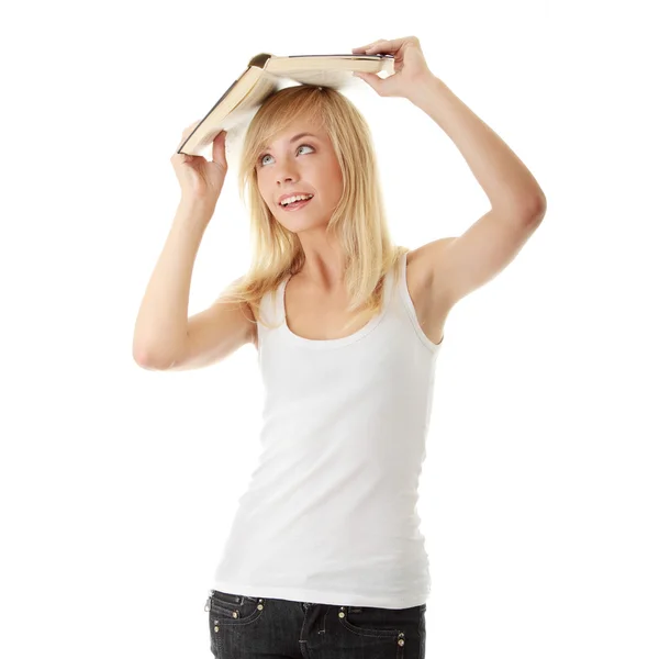 Ragazza adolescente con libro sopra la testa — Foto Stock