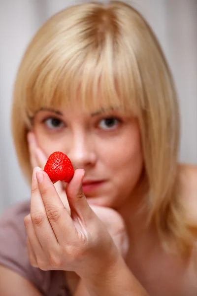 Beautiful blonde girl tempts us fresh red strawberry