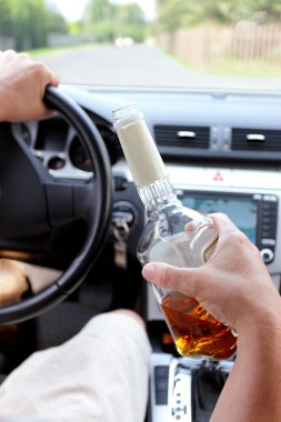 Drunk driver on a rural road with alcohol in hand clipart