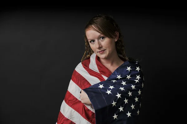 Kvinnan insvept i en flagga Stockbild