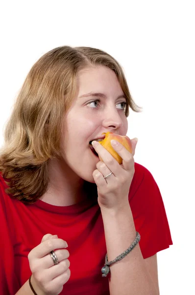 Девочка-подросток ест персик — стоковое фото