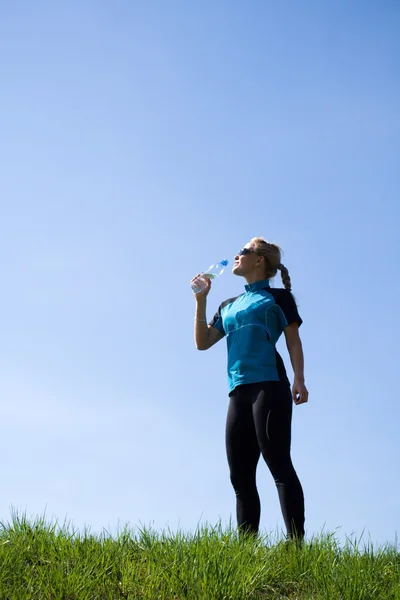 Jovem mulher bebendo água depois de correr — Fotografia de Stock