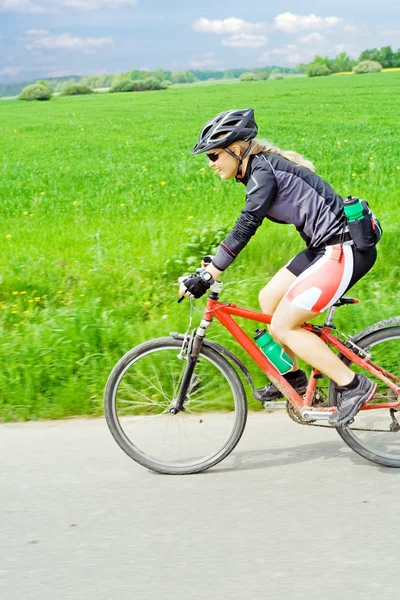 Giovane donna in sella a una mountain bike — Foto Stock
